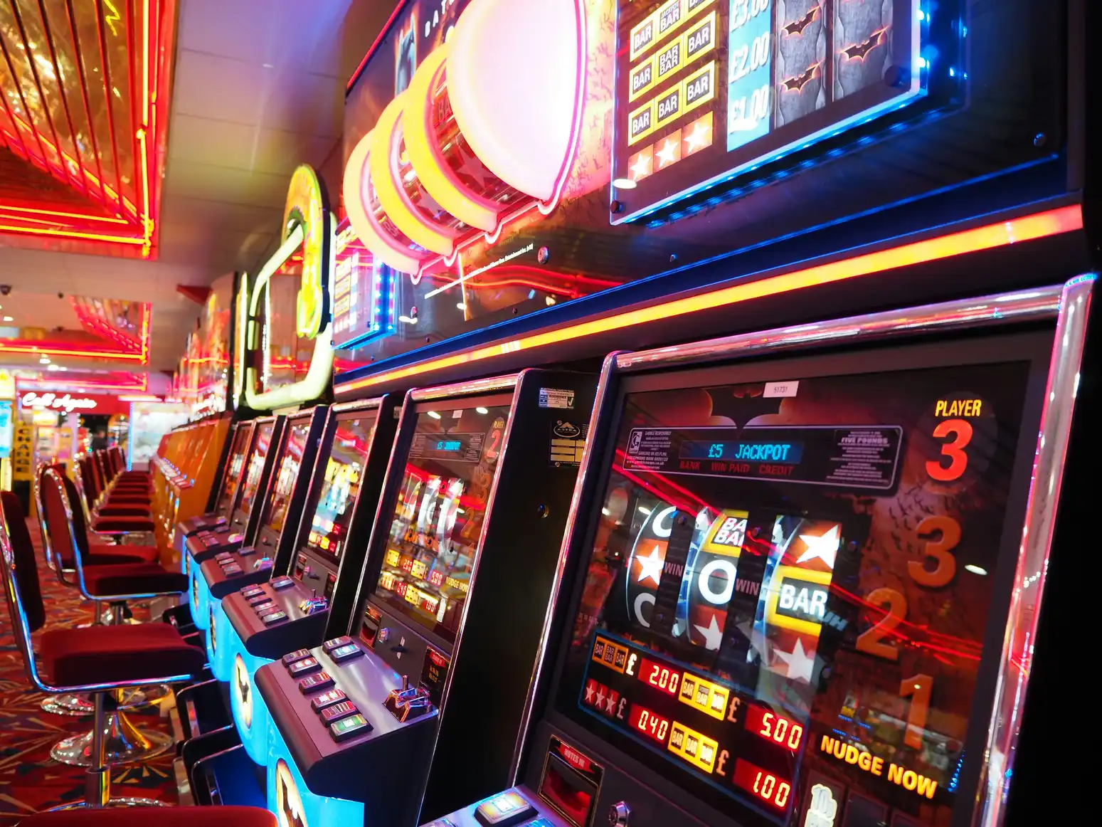 Rekke med opplyste spilleautomater på casino